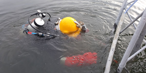 Berufstaucher beschichtet unter Wasser im See Wakeboard Mast
