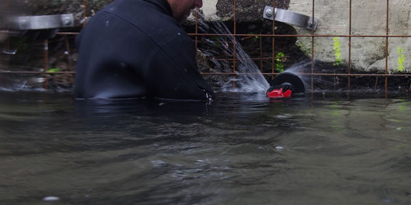 Građevinski ronilac reže građevinsko željezo Nemo kutnom brusilicom u vodi
